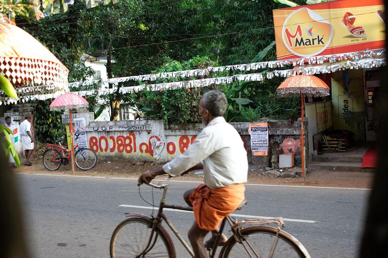 Man on a bike riding past a religious festival in Kurumassery, Ernakulam, Kerala, India