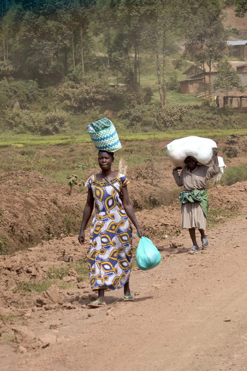 Woman walking along the street with a colorful basket on her head, Uganda