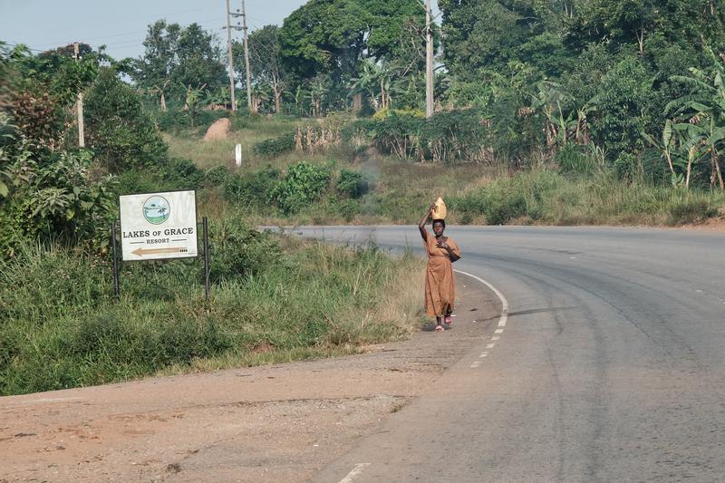 Woman walking down the street while balancing a water jug on her head, Entebbe, Uganda