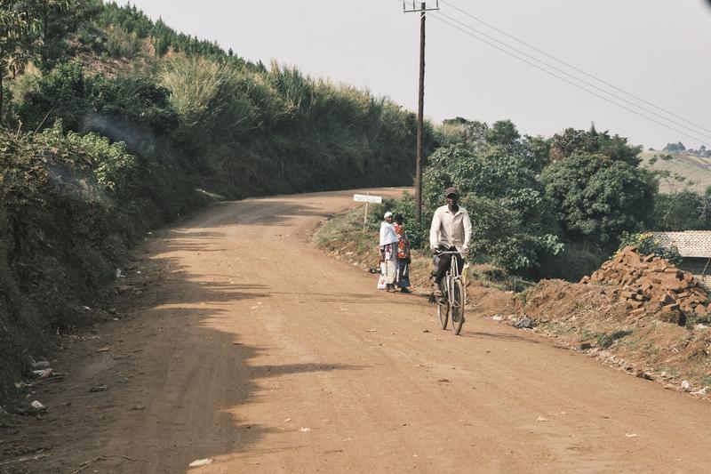 Person riding a bicycle on a dirt road, Uganda