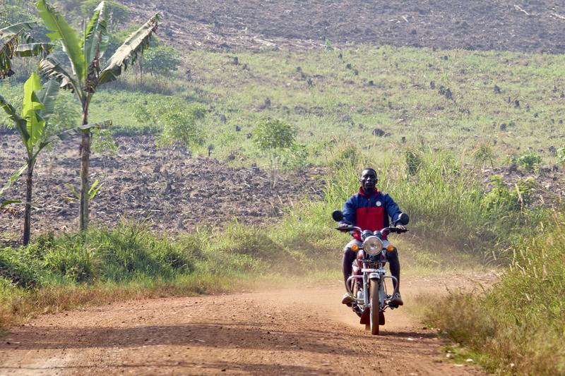 Person riding a motorcycle on a dirt road, Uganda