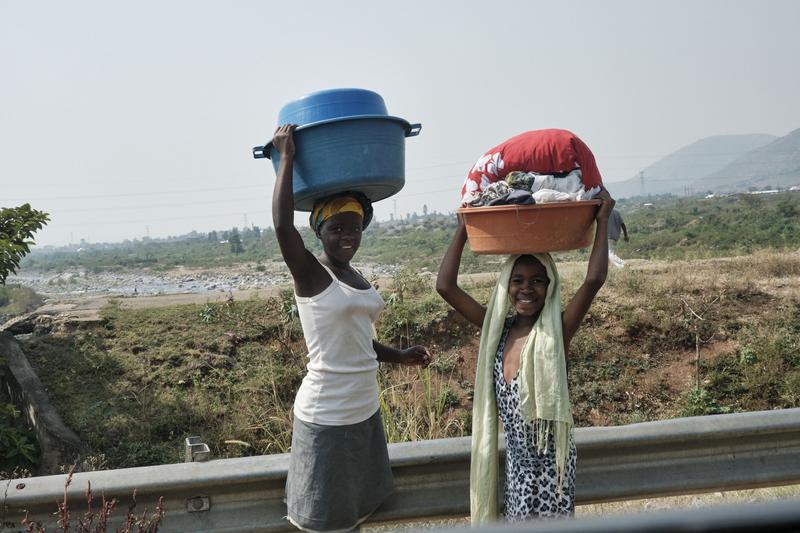 Kids carrying laundry baskets on their heads, Uganda