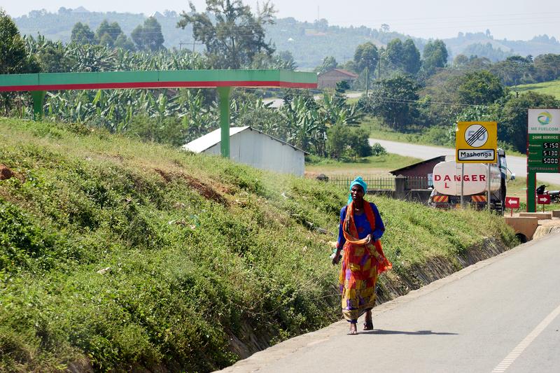 Person wearing colorful clothes walking to the side of the road, Uganda