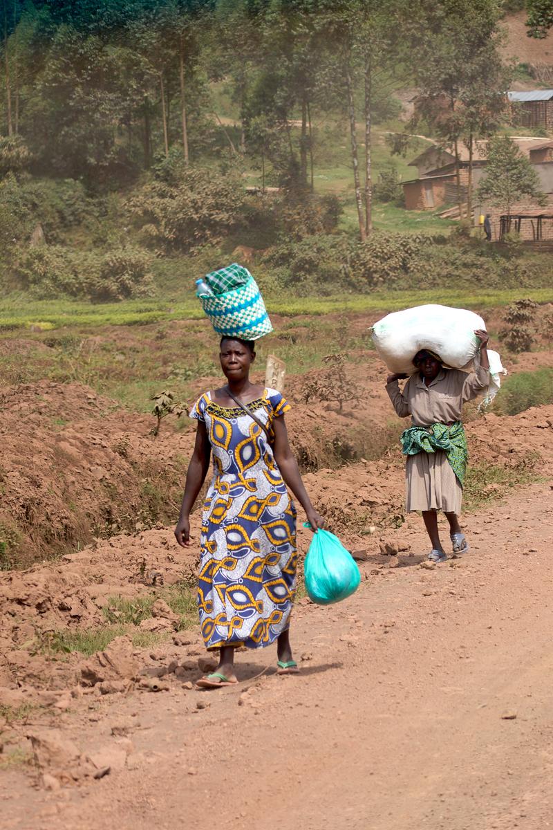Woman walking along the street with a colorful basket on her head, Uganda