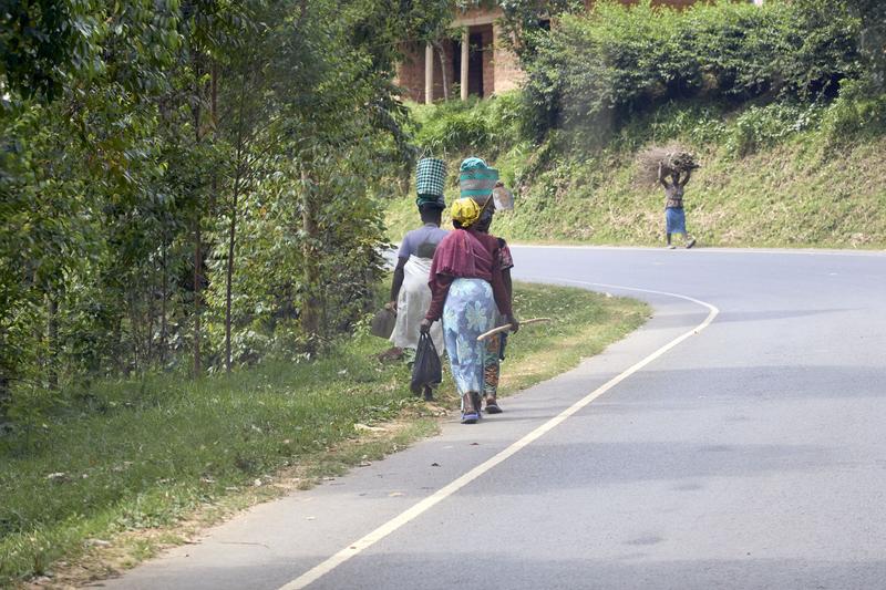 Women walking along the street with colorful baskets on their head, Uganda
