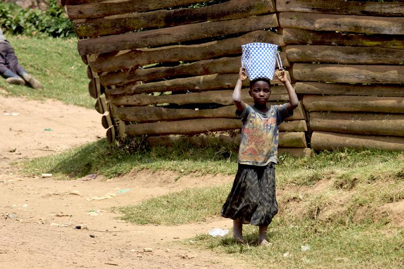 Kid carrying a bucket on their head, Uganda